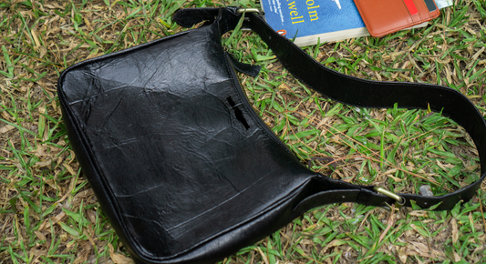 a book and a book bag laying on the grass